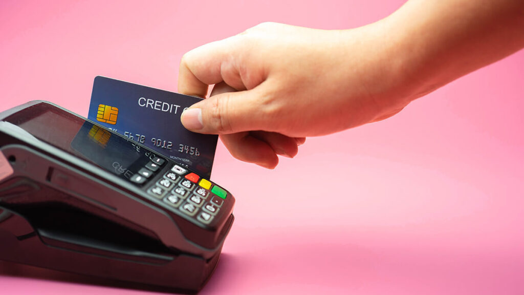 main qui insère une carte bancaire dans la bande magnétique d'un terminal de paiement